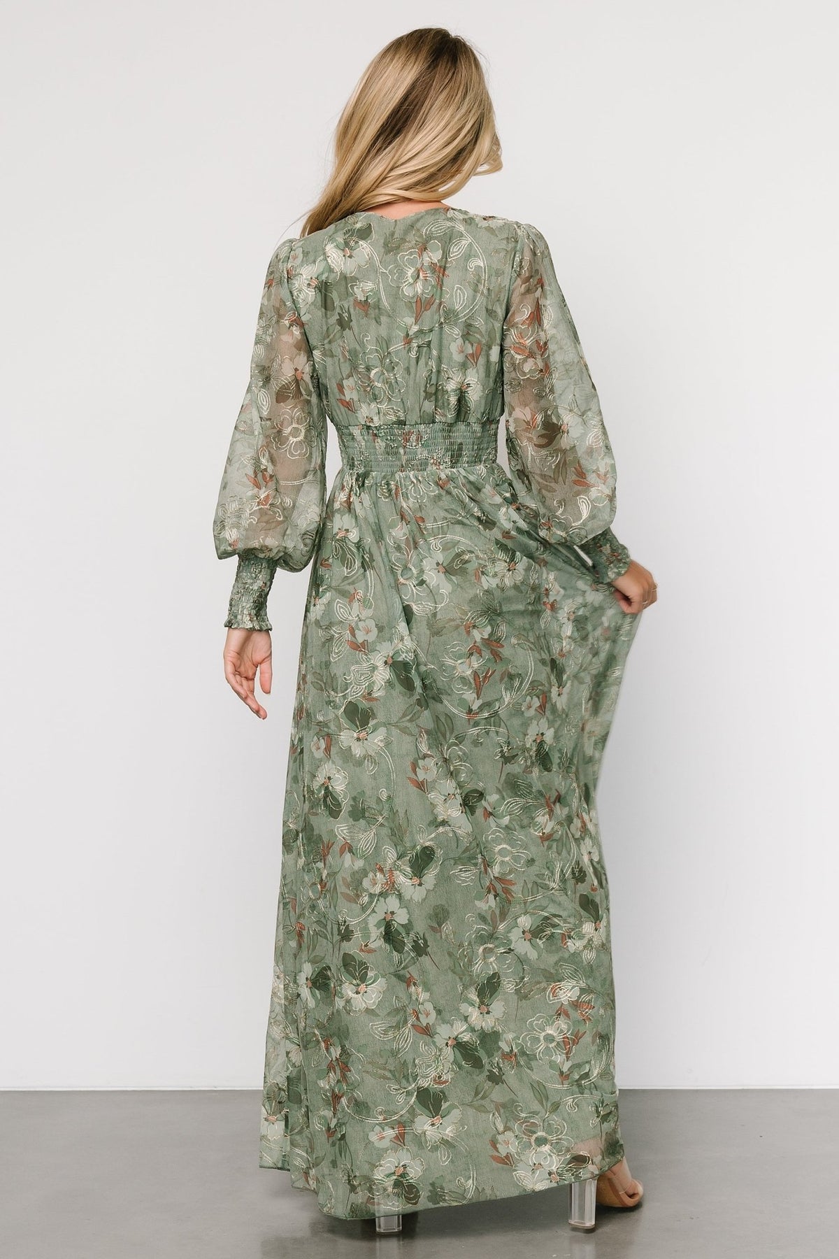 Three-quarter view of sage tulle dress showing smocked waist, sheer long sleeves, and embroidered floral pattern.