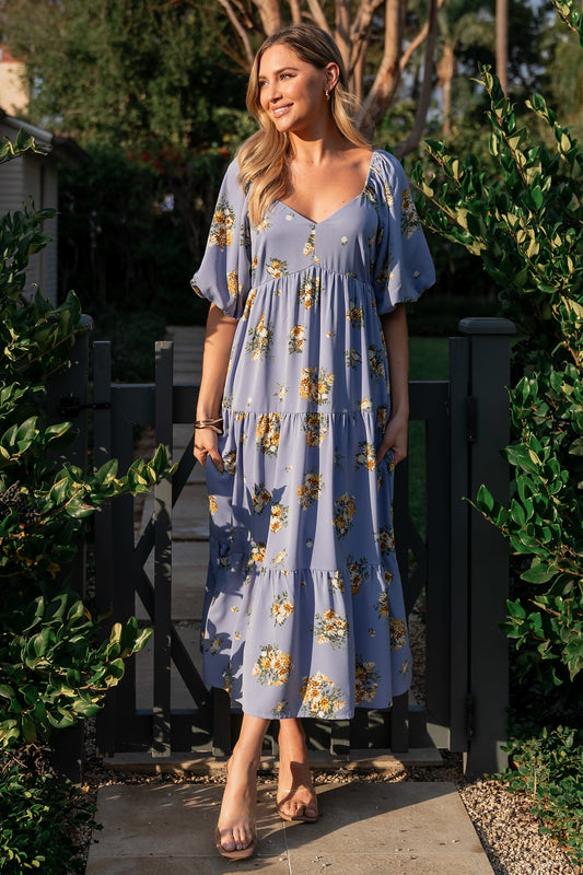 Front view of Judith chiffon midi dress in blue-purple with golden floral print, V-neckline, empire waist and tiered lined skirt for movement.