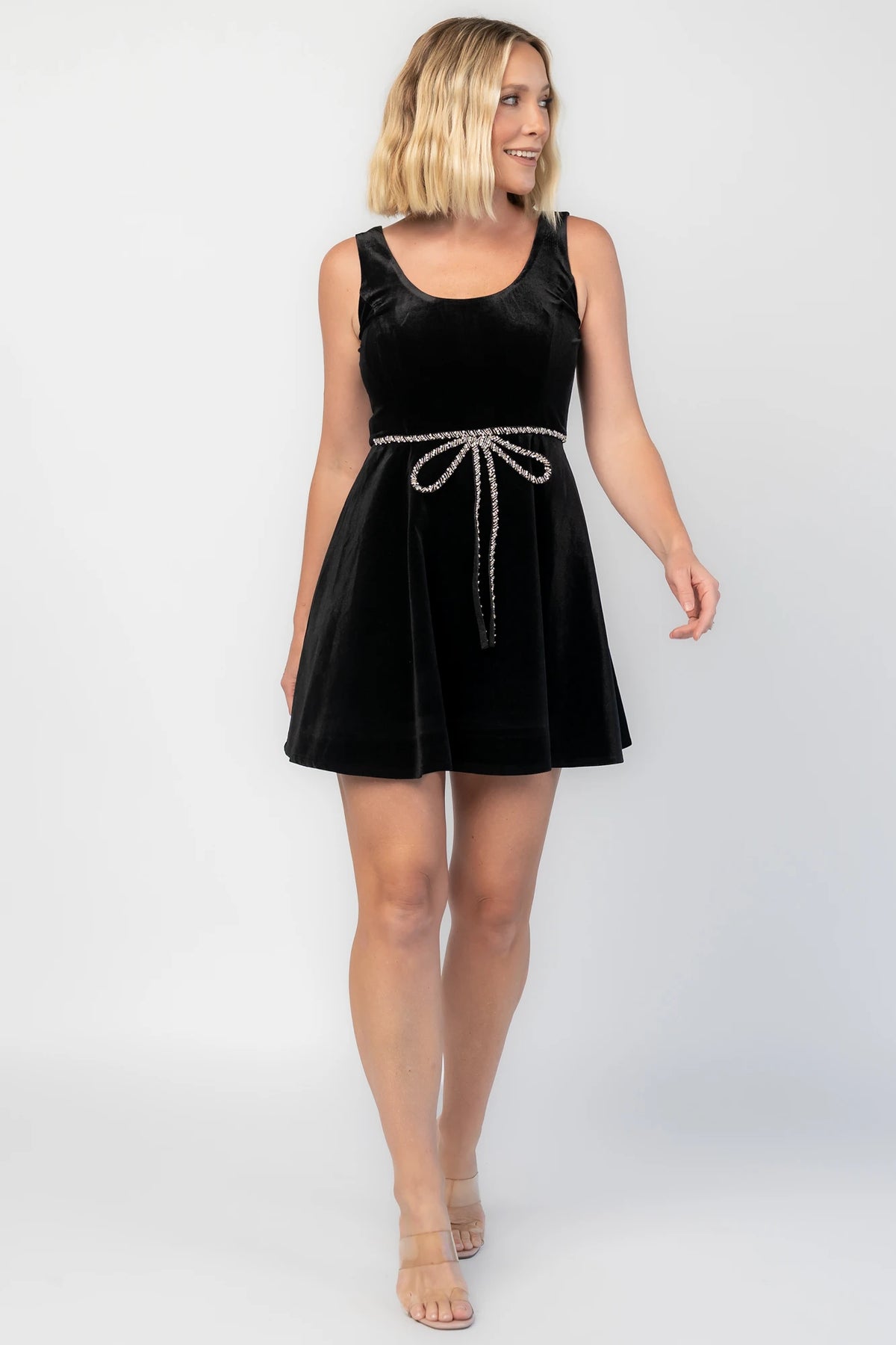 Julieta Short Dress in Black with a velvet finish, scoop neckline, and a rhinestone bow at the front waist.