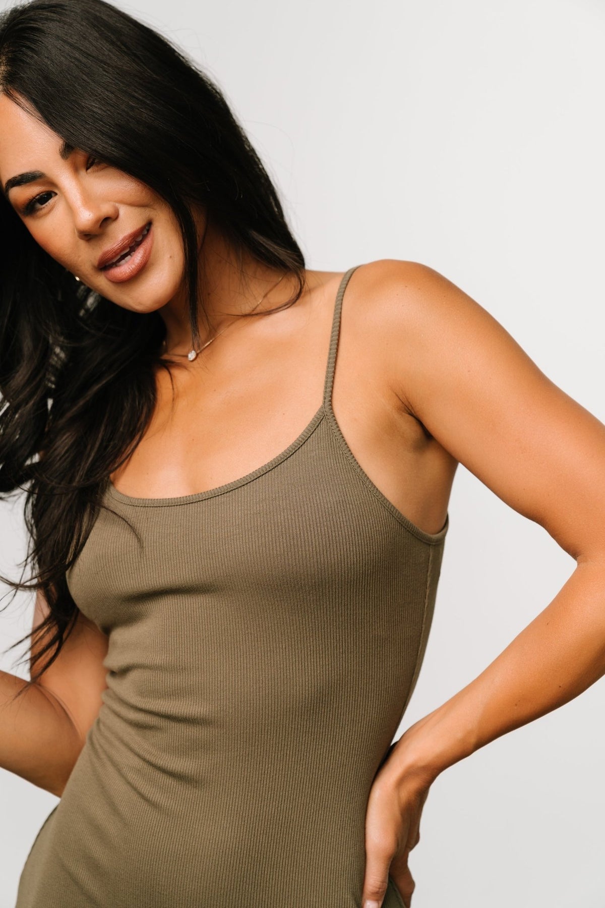 Model walking in the Kade bodycon tank dress in dusty olive, showing movement and how the left-side slit falls above the knee.