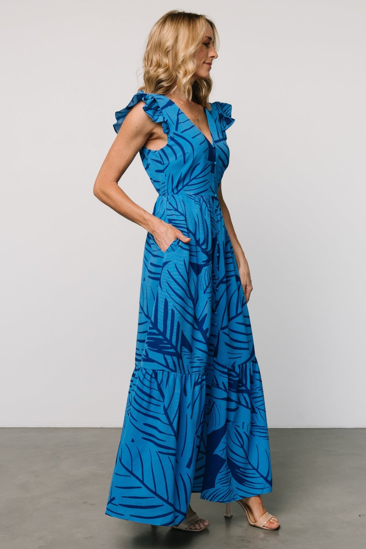 Side view of Kaia Button Maxi Dress in blue print highlighting cap-style flutter sleeve, subtle waist gathering, and discreet side pocket.