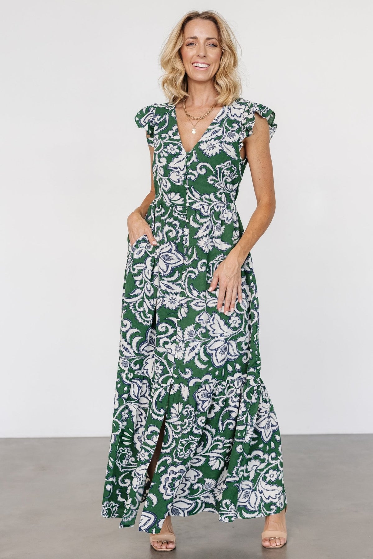 Full-length studio shot of Kaia Button Maxi Dress in green print on model, displaying V-neckline, gathered waist, and maxi length.