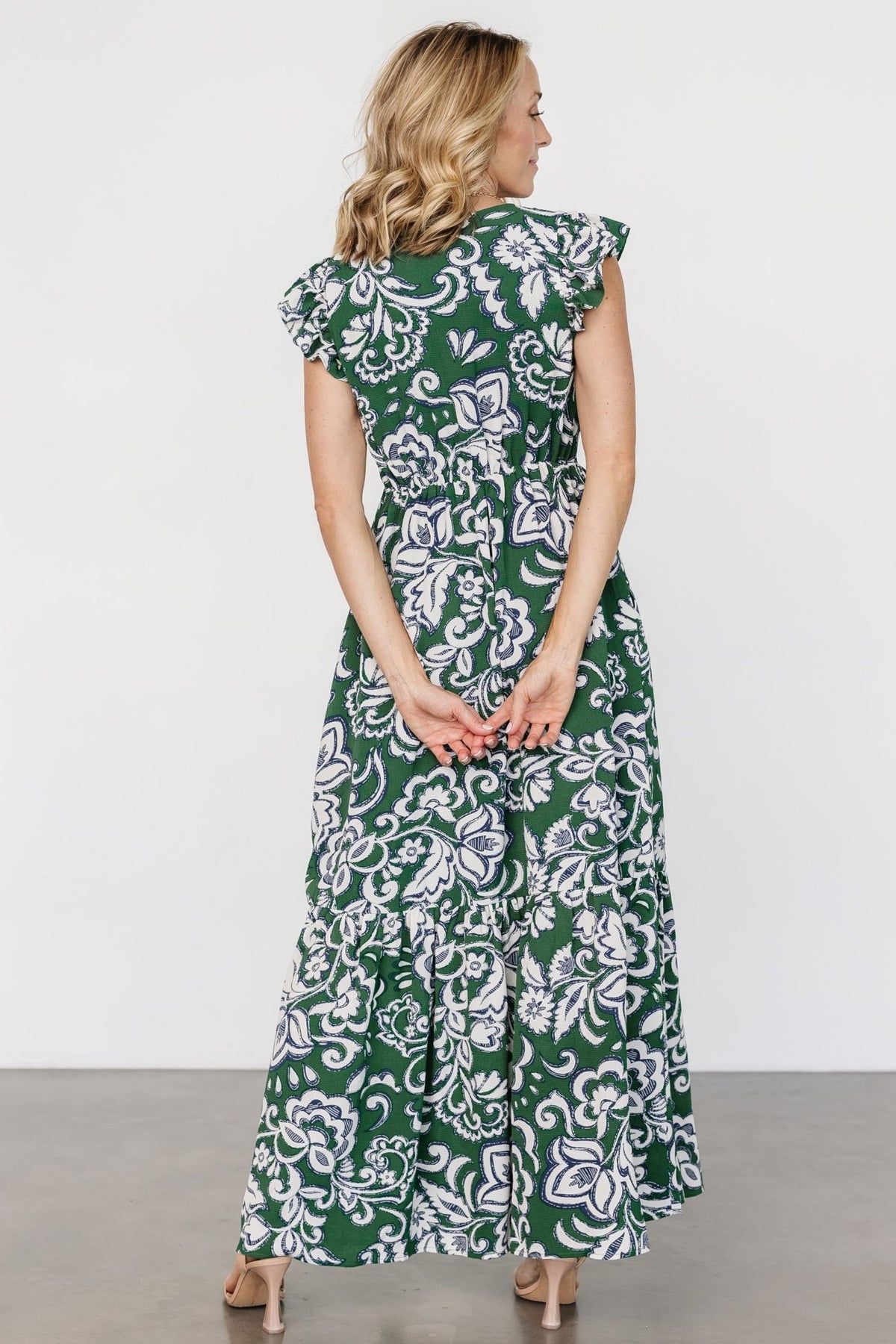 Back and movement shot of Kaia Button Maxi Dress to show skirt length, single tier detail, and flowy silhouette in green botanical print.