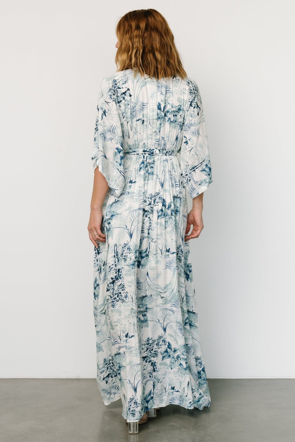 Back view of Kalea maxi dress in blue-and-white botanical print with loose-fitting kimono sleeves and mid-thigh lining visible.