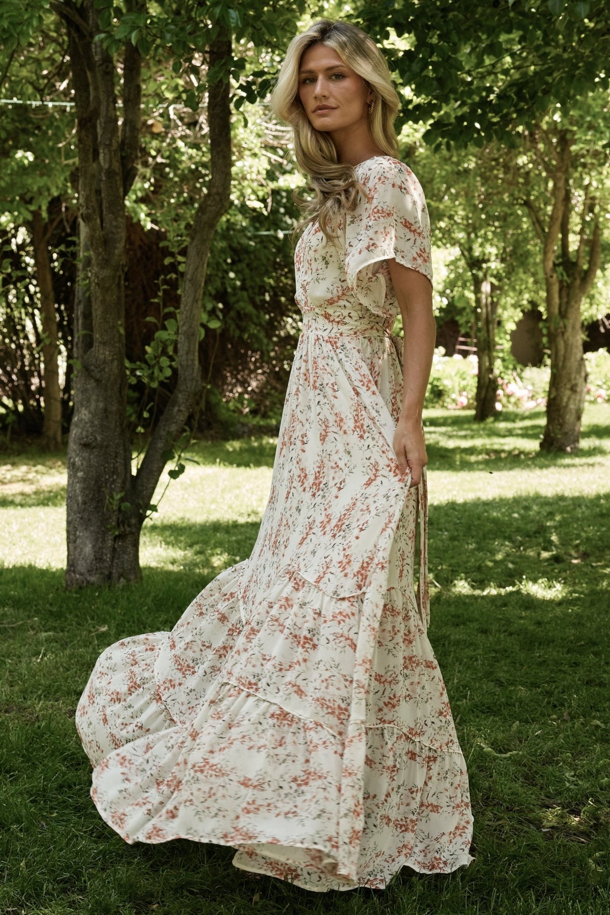 Back view showing keyhole closure and attached side ties on the cream and rust floral maxi dress, tiered skirt visible.