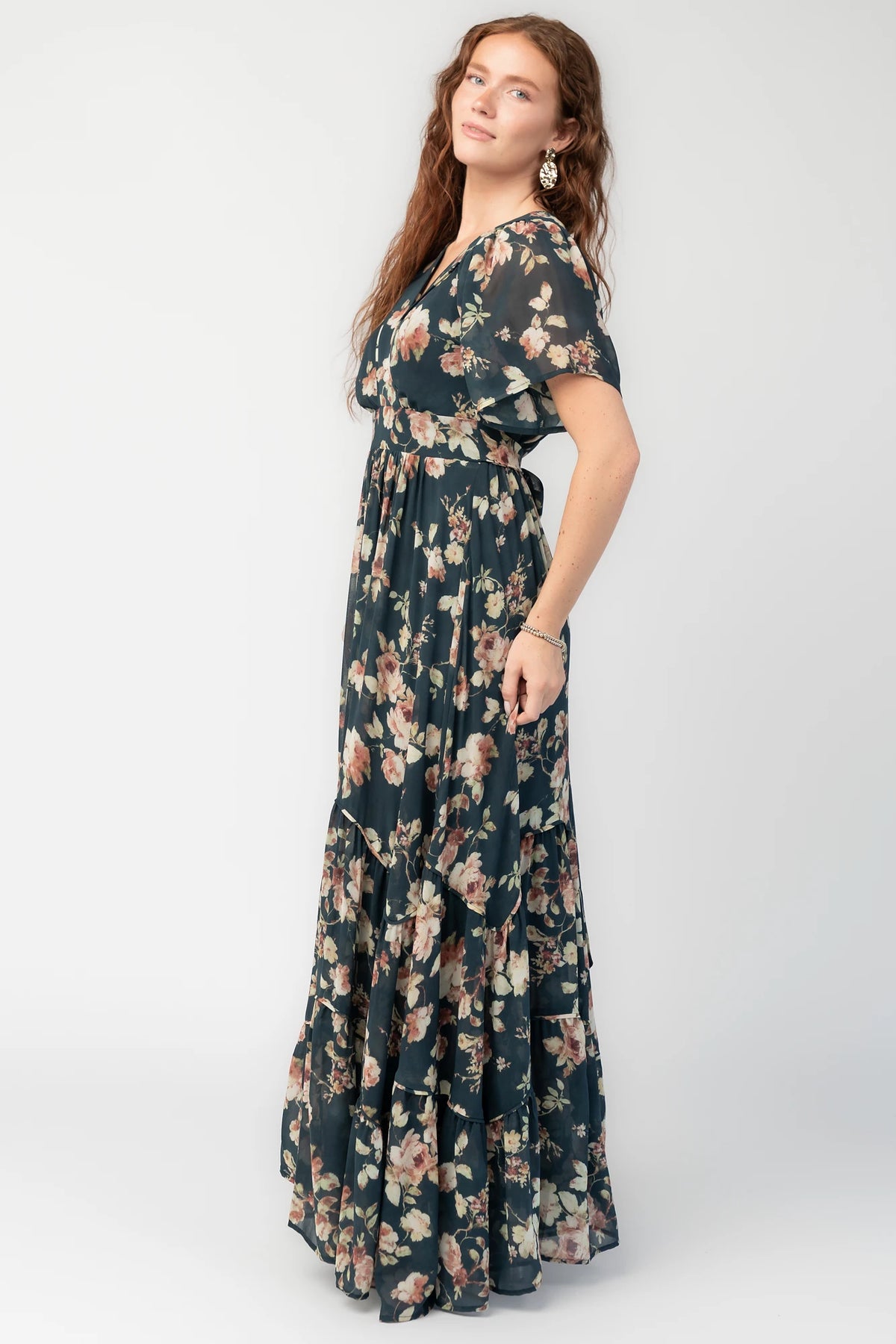 Katherine Maxi Dress in Deep Blue Floral with surplice V-neck, flutter sleeves, adjustable waist ties, and tiered skirt.