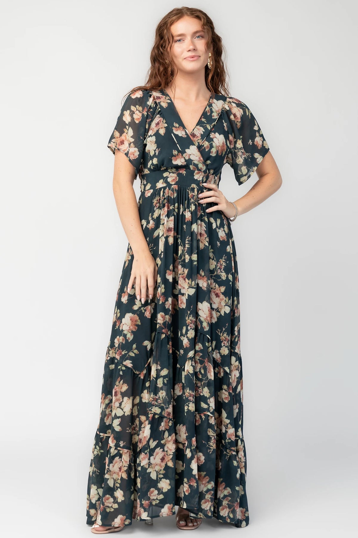 Katherine Maxi Dress in Deep Blue Floral with surplice V-neck, flutter sleeves, adjustable waist ties, and tiered skirt.