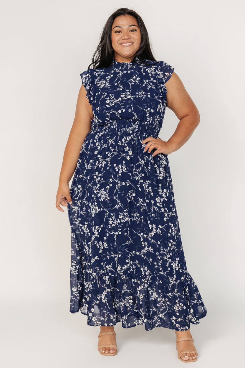 Three-quarter angle showing smocked waist and flowing chiffon skirt in blue floral print, highlighting ruffle detail and gentle drape.