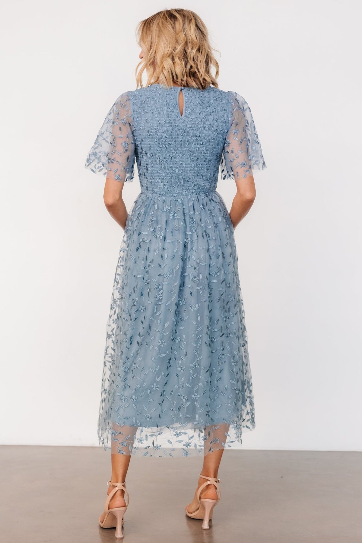 Side profile of dusty blue midi dress with subtle gathered natural waist and midi-length skirt, demonstrating soft drape and movement.