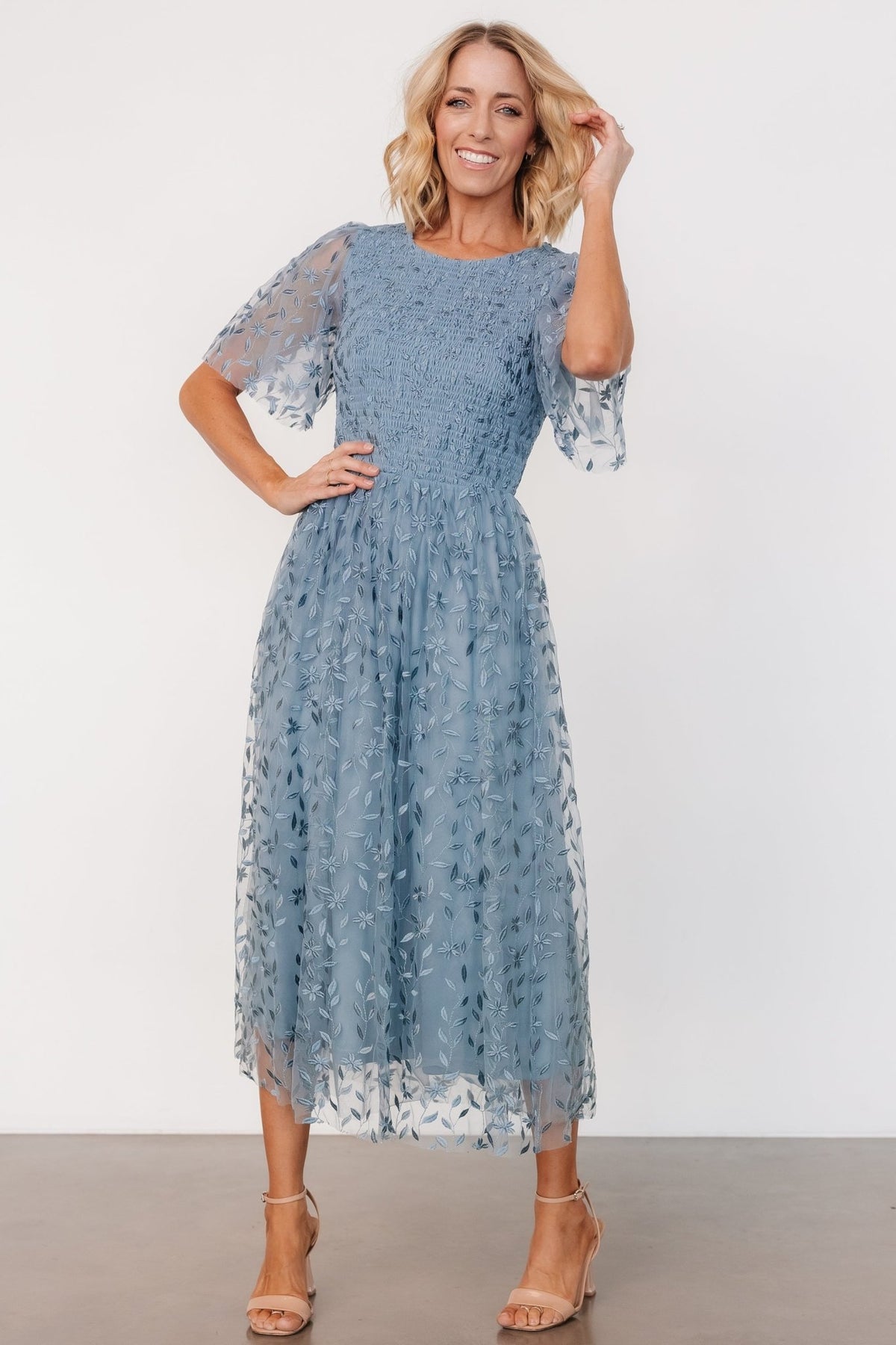 Fabric detail shot of dusty blue embroidered tulle and lining showing self fabric blend and the lightweight 100% polyester lining beneath the tulle.