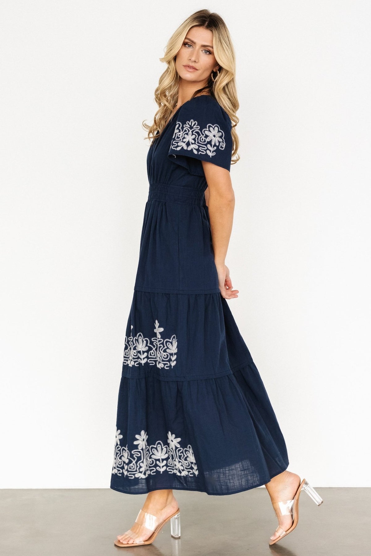 Back view of blue tiered maxi dress showing skirt tiers, embroidered detailing continuing around the hem, and unlined bodice.