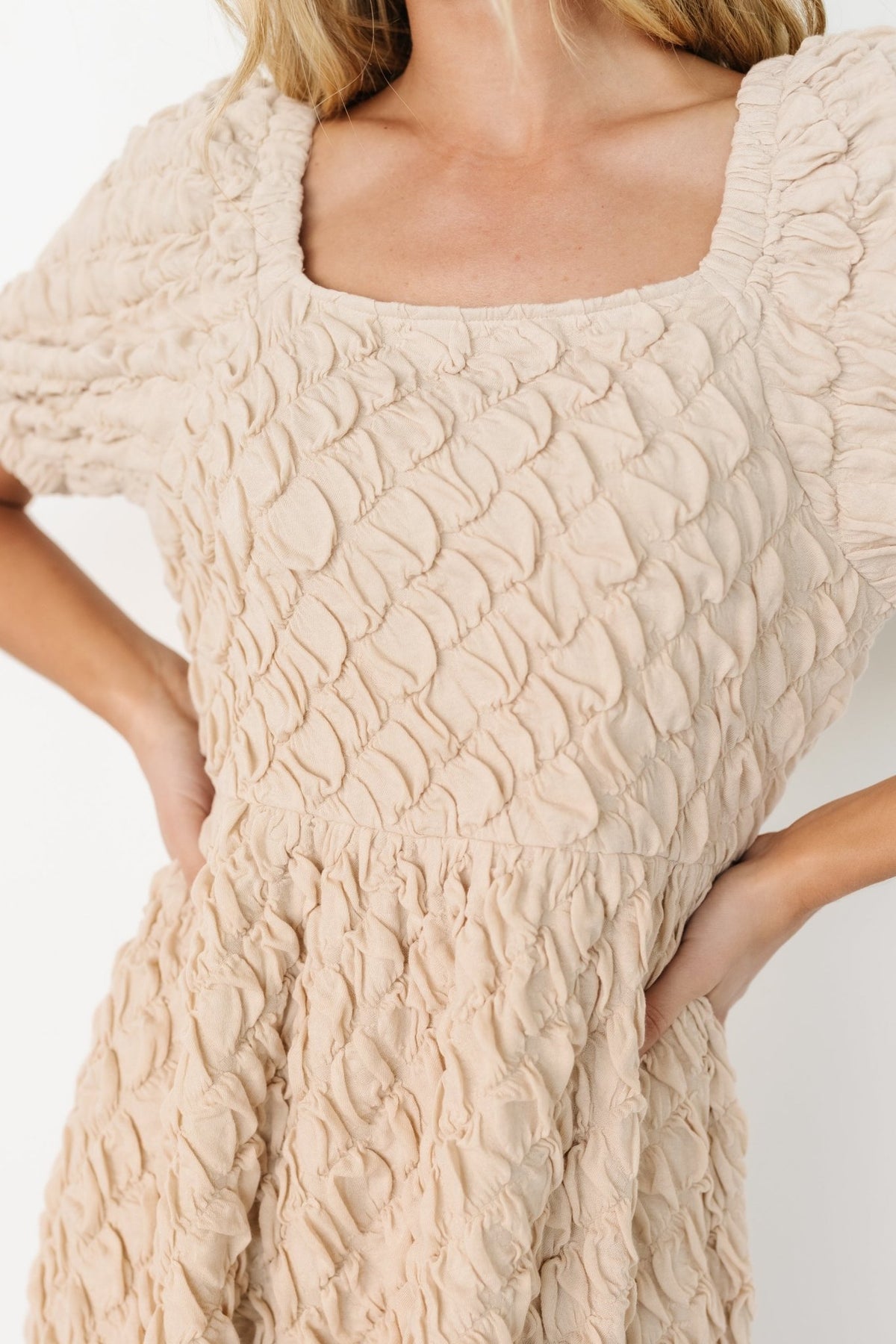 Side view of the midi dress showing the natural waist, flowing circle skirt, and gentle swing of the fabric as the model moves across the frame.