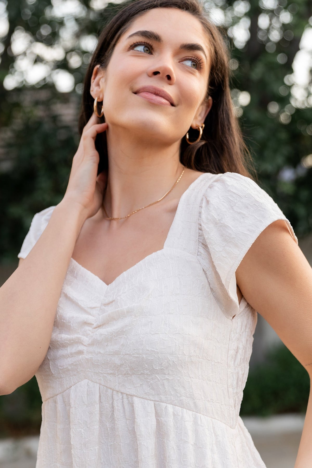 Detail shot of cap flutter sleeve and upward pointed empire waist on the cream Kesler Midi Dress, showing fabric texture.