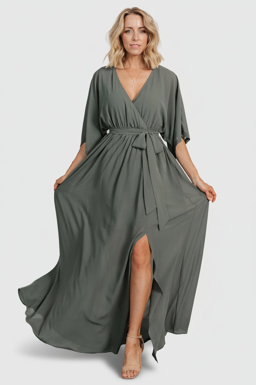 Model wearing dark sage Kia kimono maxi dress with self-tie sash visible at elastic waistband, styled for occasion wear.