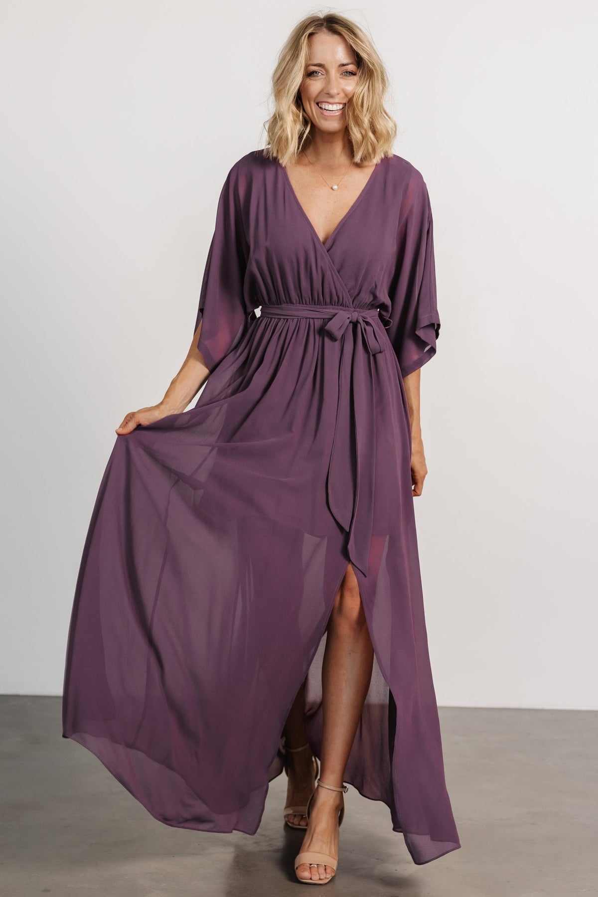 Model wearing Kia Kimono Maxi Dress in vintage plum, front view showing surplice neckline, kimono sleeves, and left-side leg slit for movement.