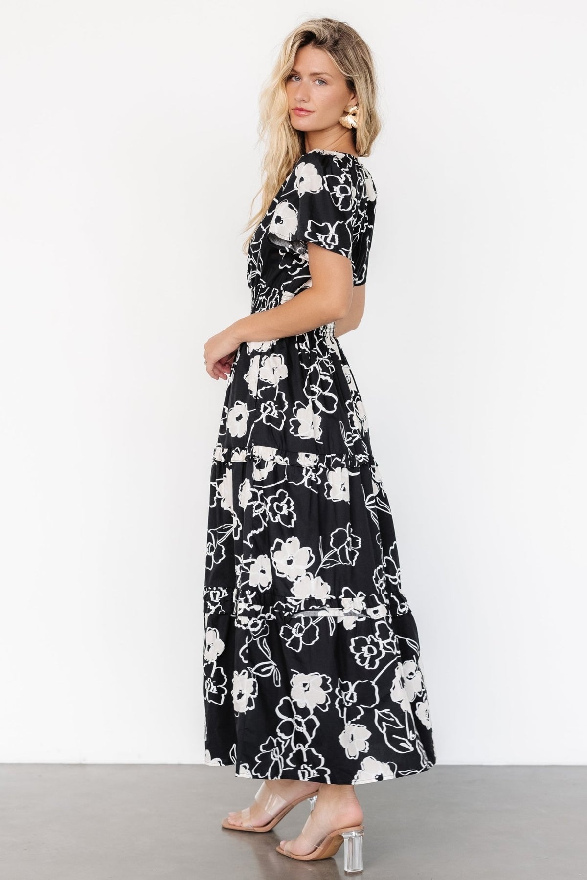 Model wearing the Kiana Poplin Maxi Dress in black and cream—full-length shot shows V-neck, smocked waist, and flowing tiers for styling.