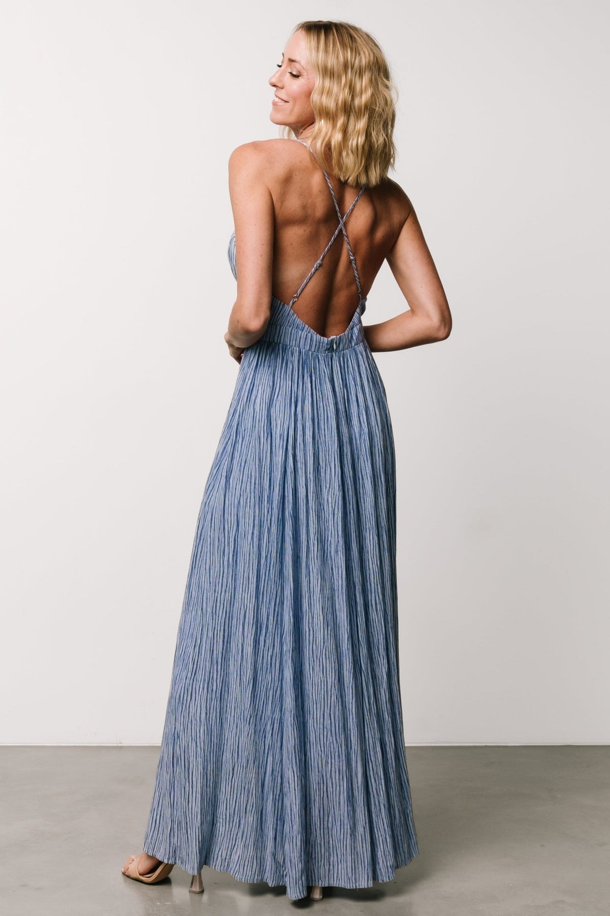 Three-quarter view of Korley Maxi Dress in blue stripe showing silhouette, adjustable straps and full skirt movement on model.