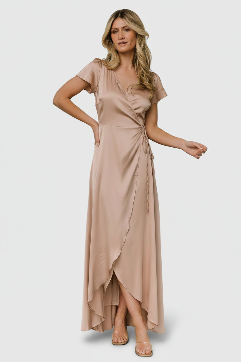 Front view of a model wearing the Krystal satin wrap gown in champagne, V-neckline, adjustable tie waist, floor-length tulip skirt and graceful drape.