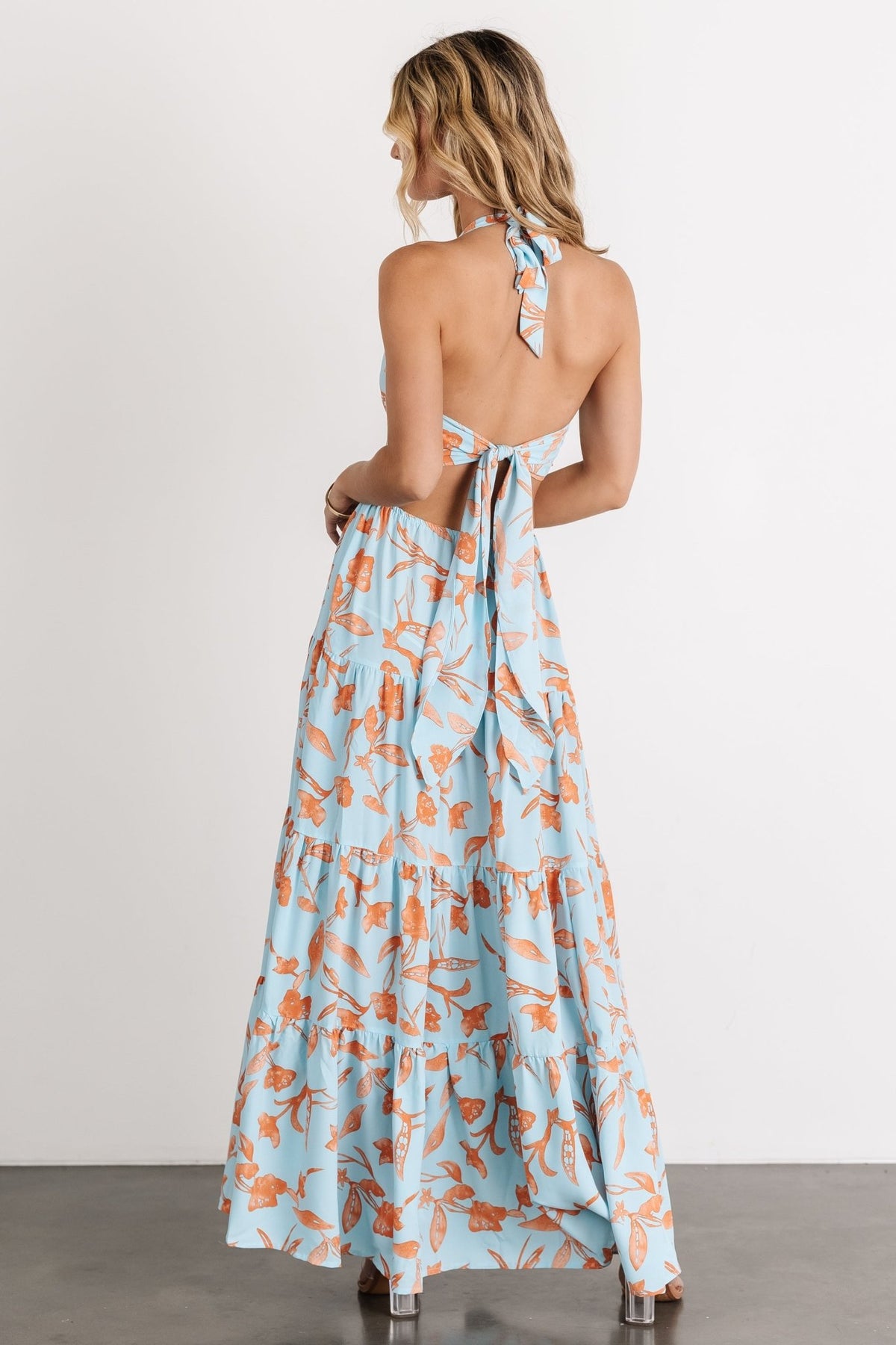 Close-up of high neckline and adjustable neck tie on blue and orange floral maxi dress, showing fabric texture and print scale.