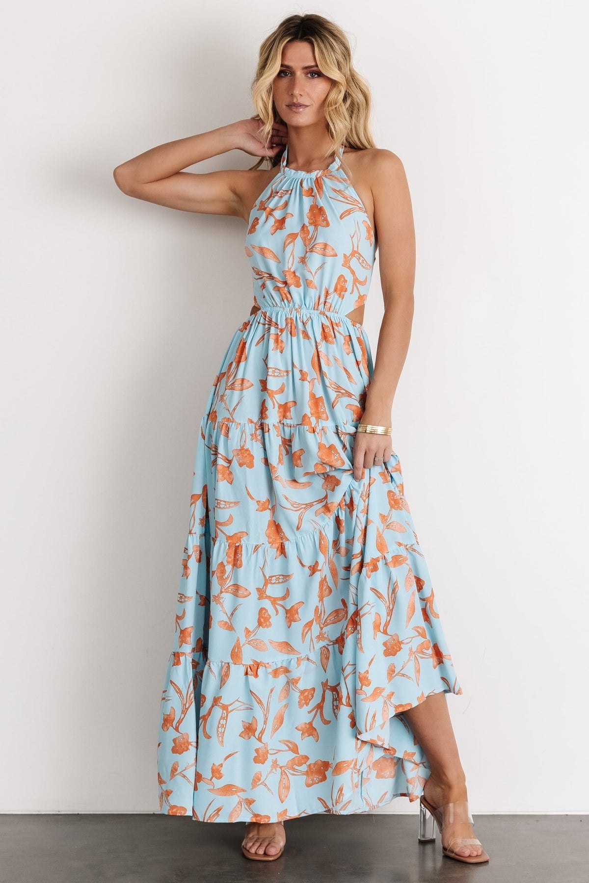 Detail shot of the dress fabric and floral pattern, highlighting light blue base with orange blossoms and gentle texture of the polyester fabric.