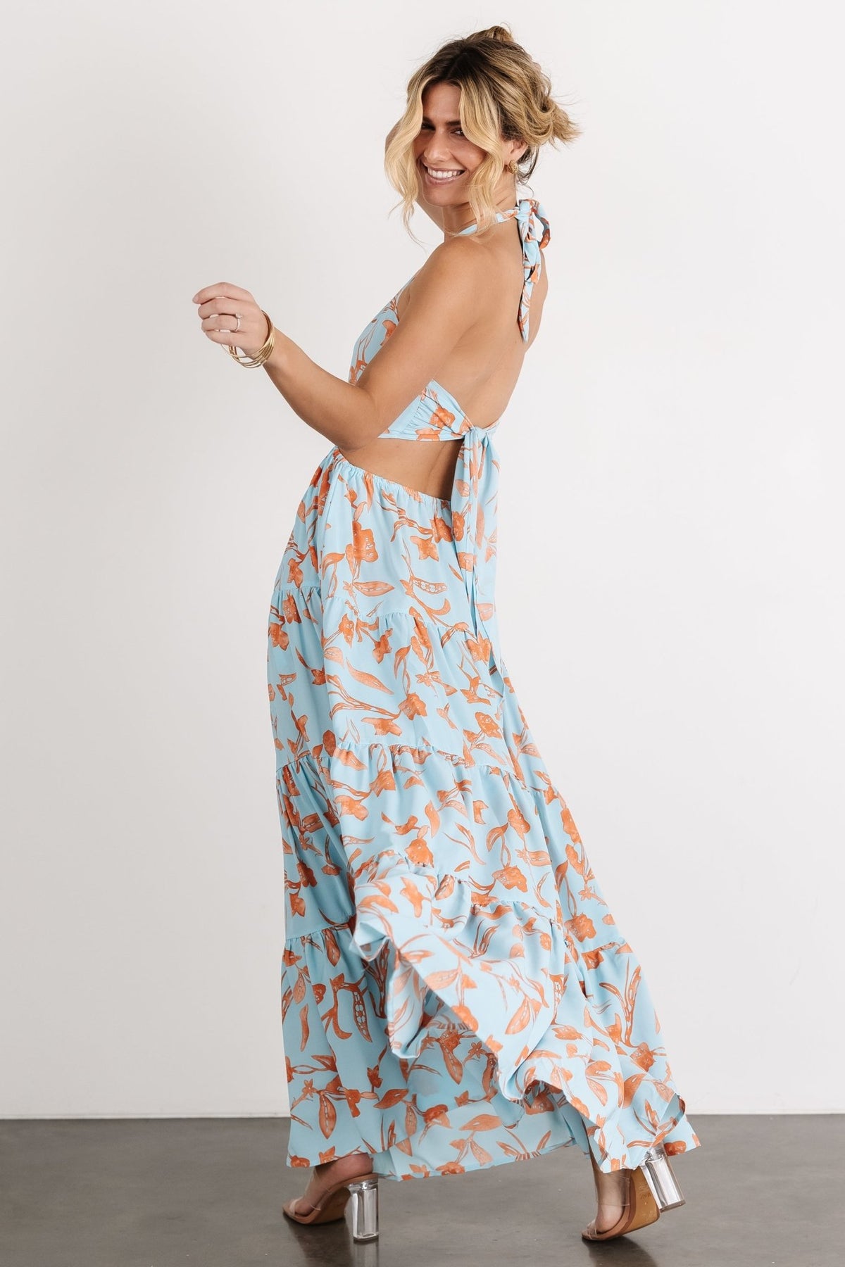 Side view of blue and orange floral maxi dress showing tiered skirt and lightweight drape, pull-on silhouette and delicate floral print in close detail.