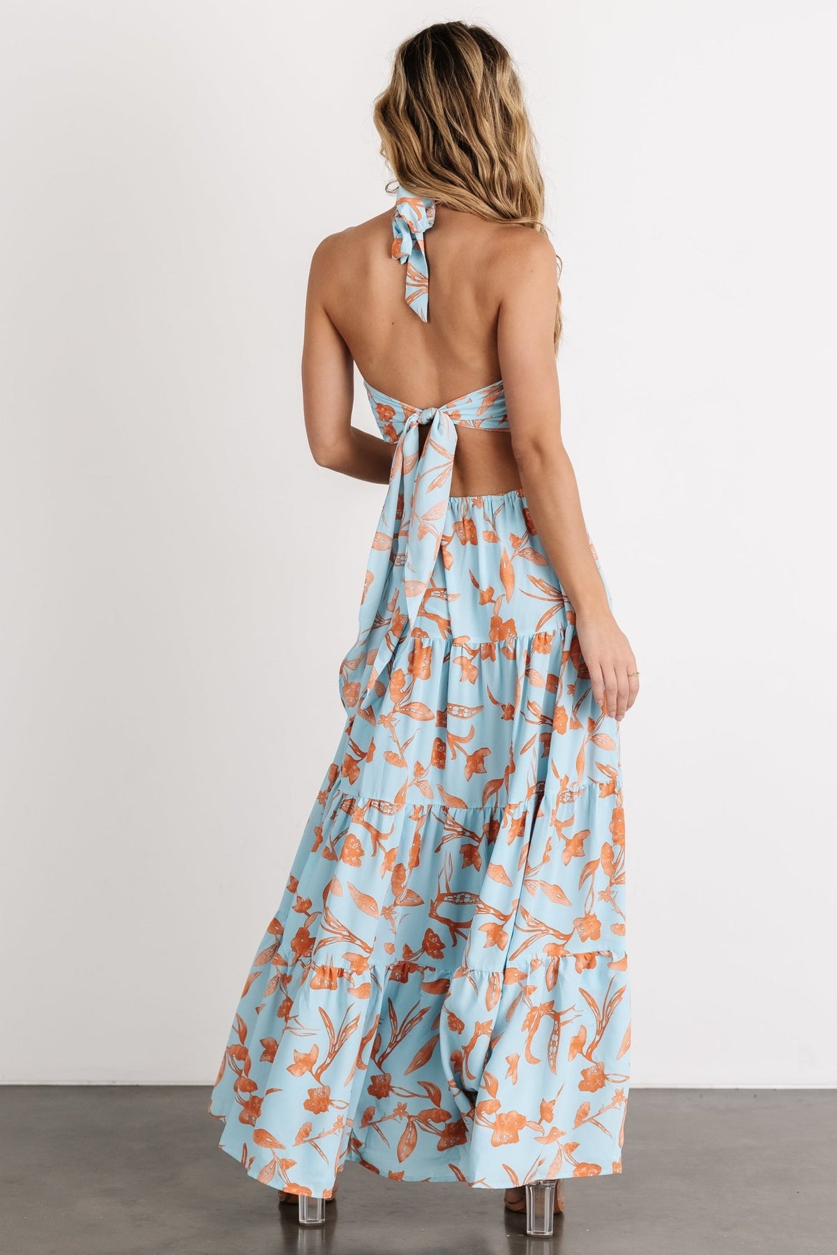 Full-length shot of the tiered maxi dress in blue with orange floral print, showing flow and movement ideal for warm-weather occasions.