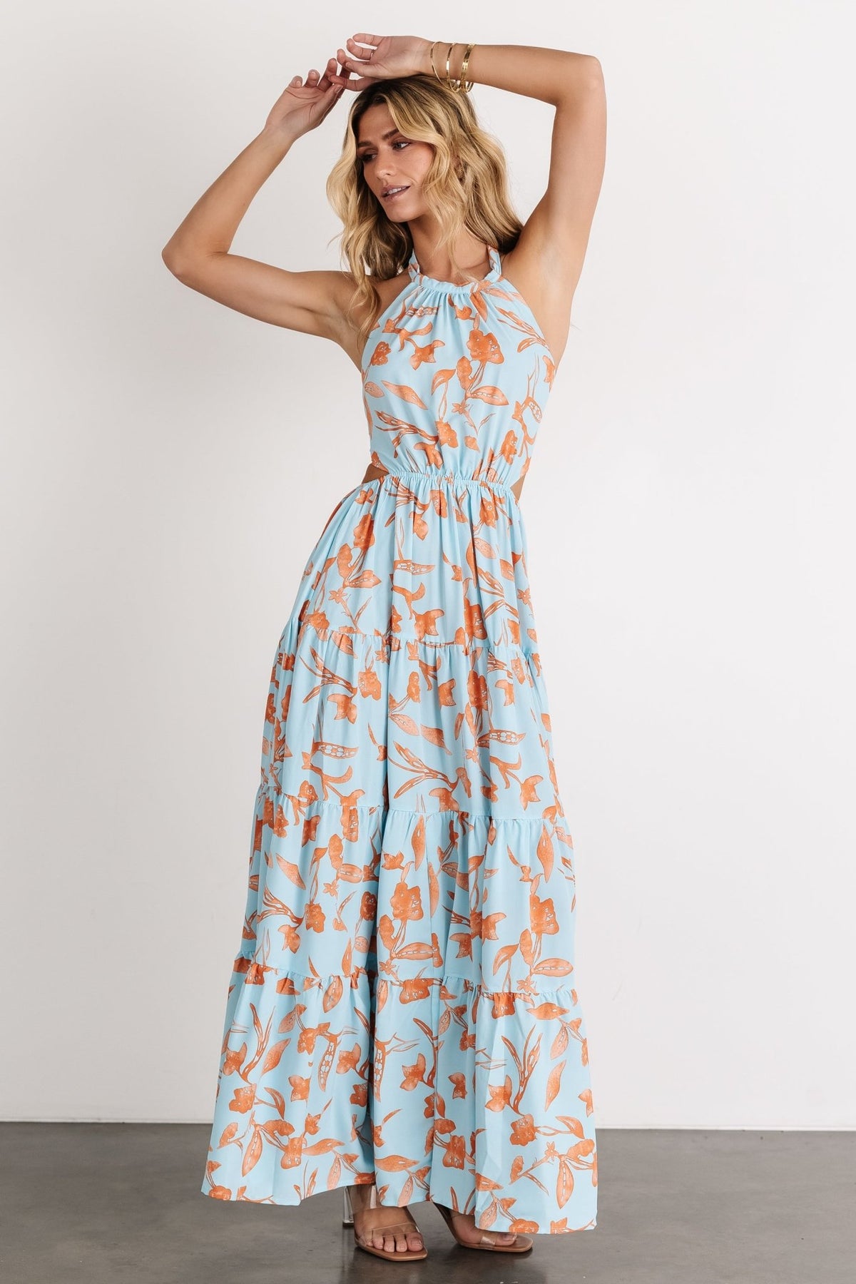 Back view highlighting open-back detail and adjustable back tie on the blue and orange floral tiered maxi dress with soft, slightly sheer fabric.