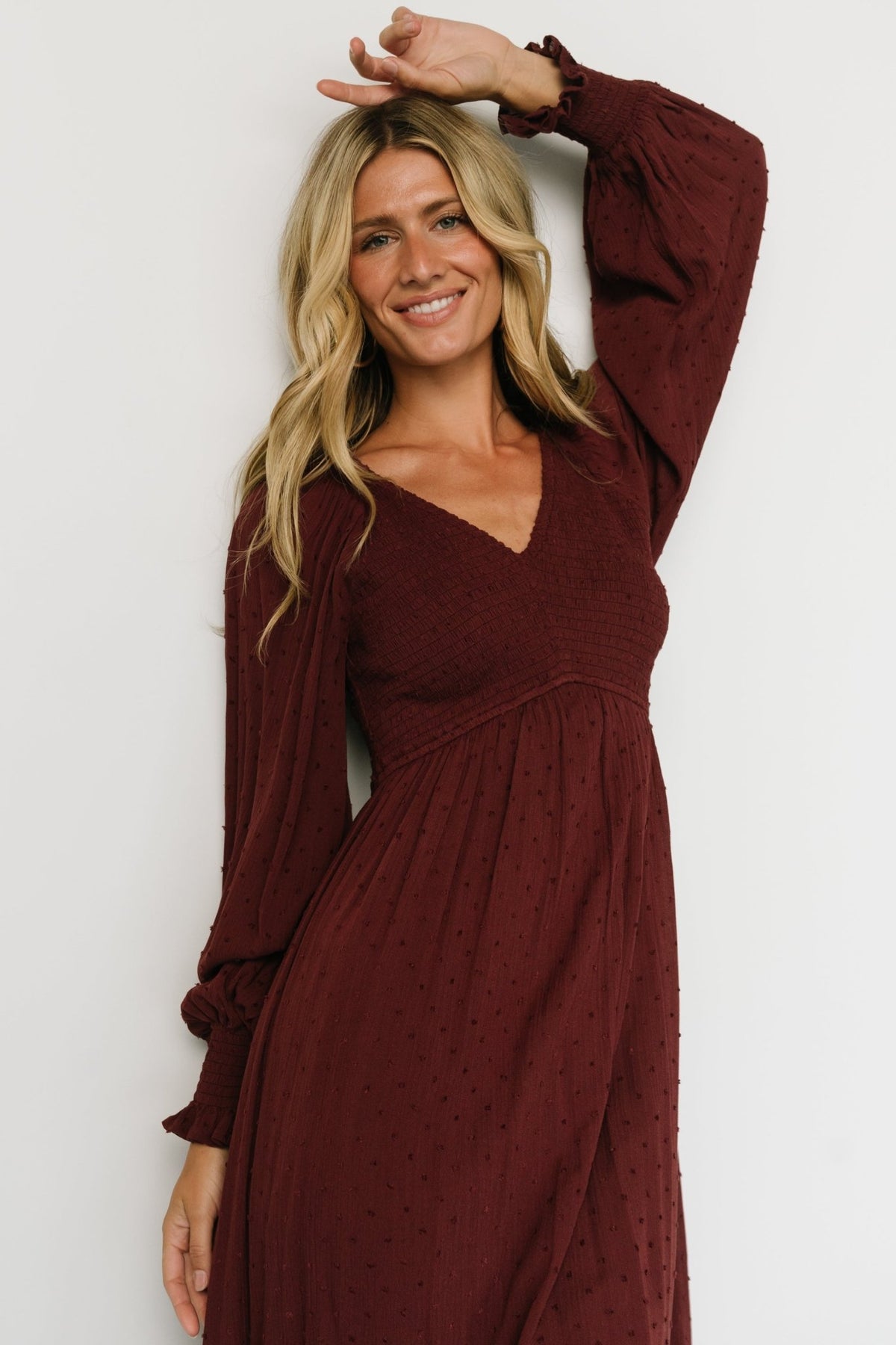 Back view of Lainey smocked dotted midi in mulberry showing smocked back bodice, elasticized waist detail, and lined skirt hem.