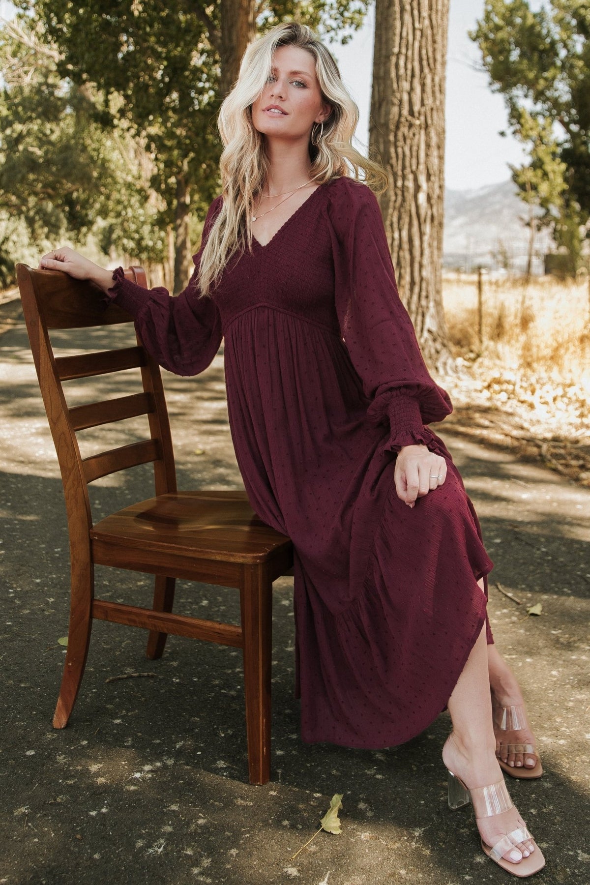 Model wearing Lainey mulberry midi dress, angled view highlighting smocked bodice, elastic shoulders, sleeve cuffs, and relaxed skirt movement.