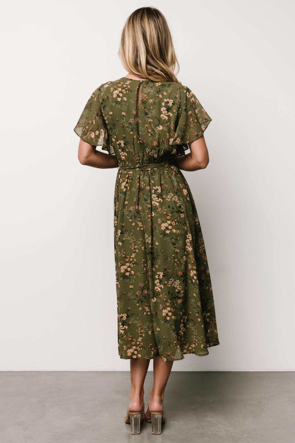 Model wearing olive floral midi dress showing overall fit, elasticized back waist, and A-line movement for a relaxed, feminine silhouette.