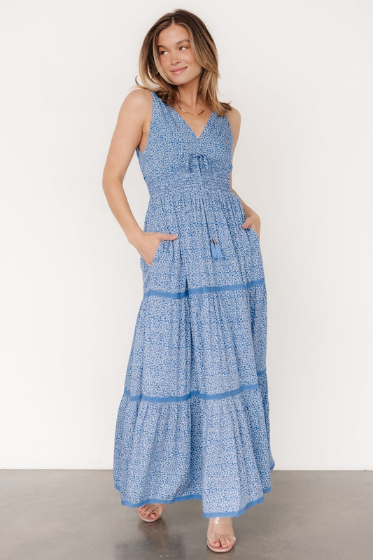 Front view of blue floral rayon maxi dress showing V-neckline, tank straps, lace tiers and a flowing full-length skirt with delicate off-white flowers.