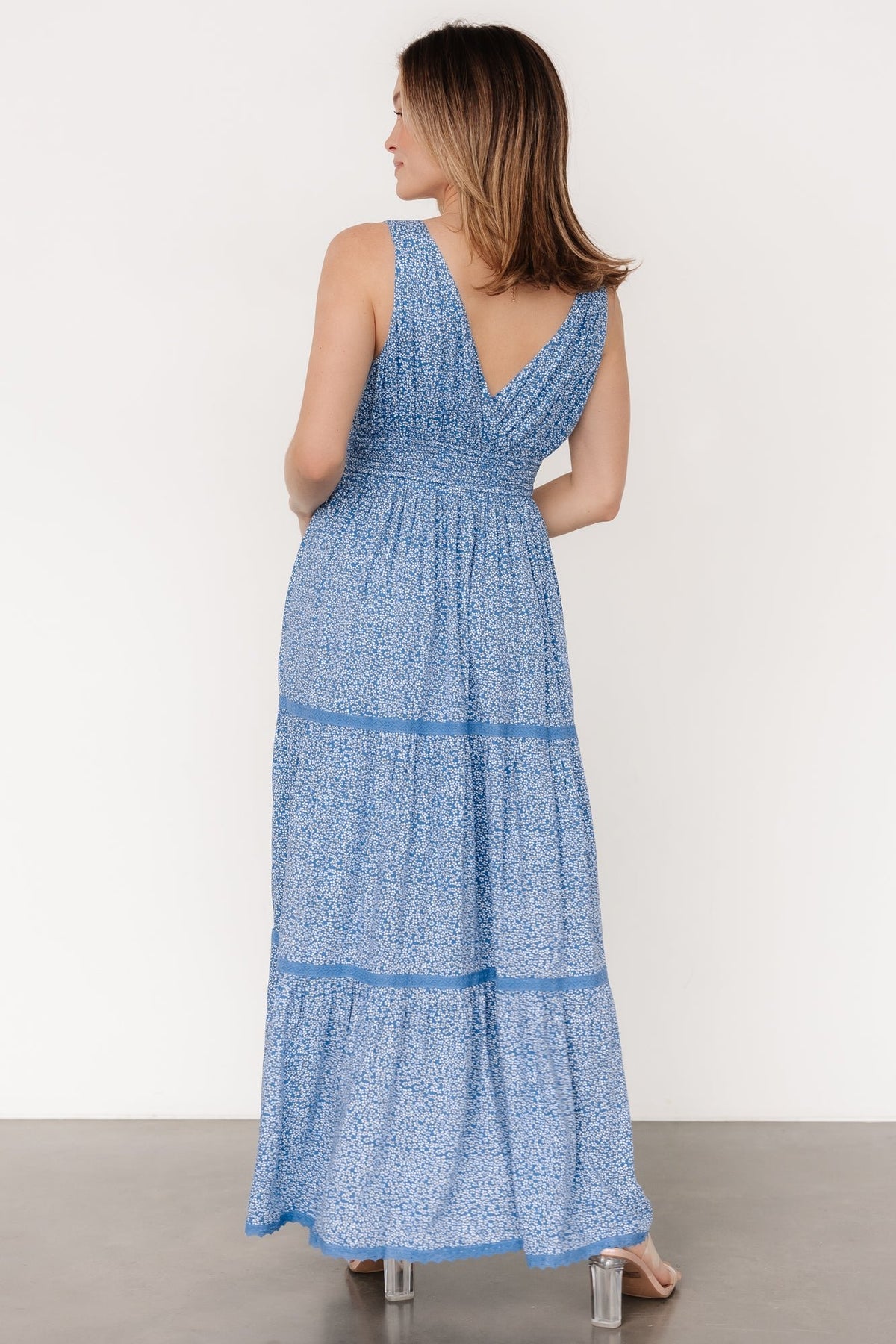 Close-up of the smocked waist and adjustable tassel ties on the blue floral rayon dress, showing texture and stitch detail of the smocking.