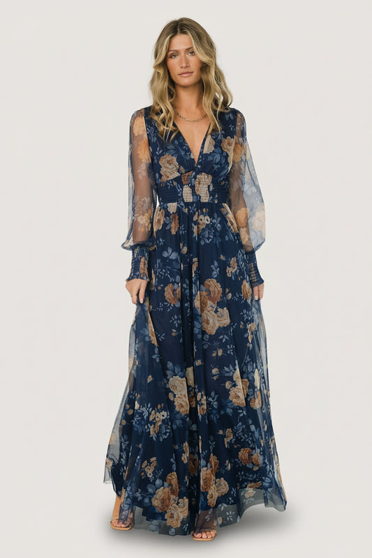 Front view of Layla tulle maxi dress in blue with golden floral pattern, showing deep V-neck, smocked waist and flowing layered skirt.