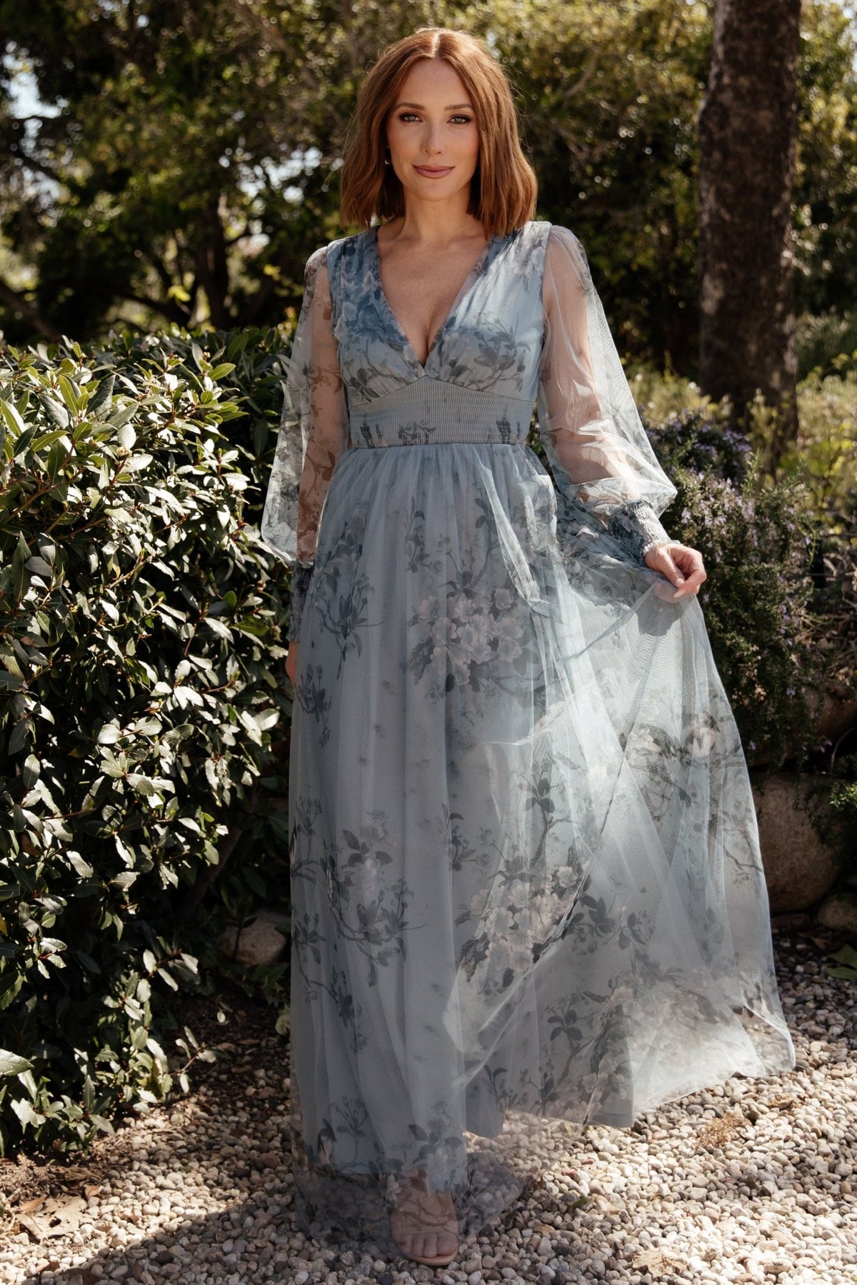 Close-up of bodice highlighting deep V-neckline, delicate floral print on tulle, and smocked detailing at waist and sleeves.