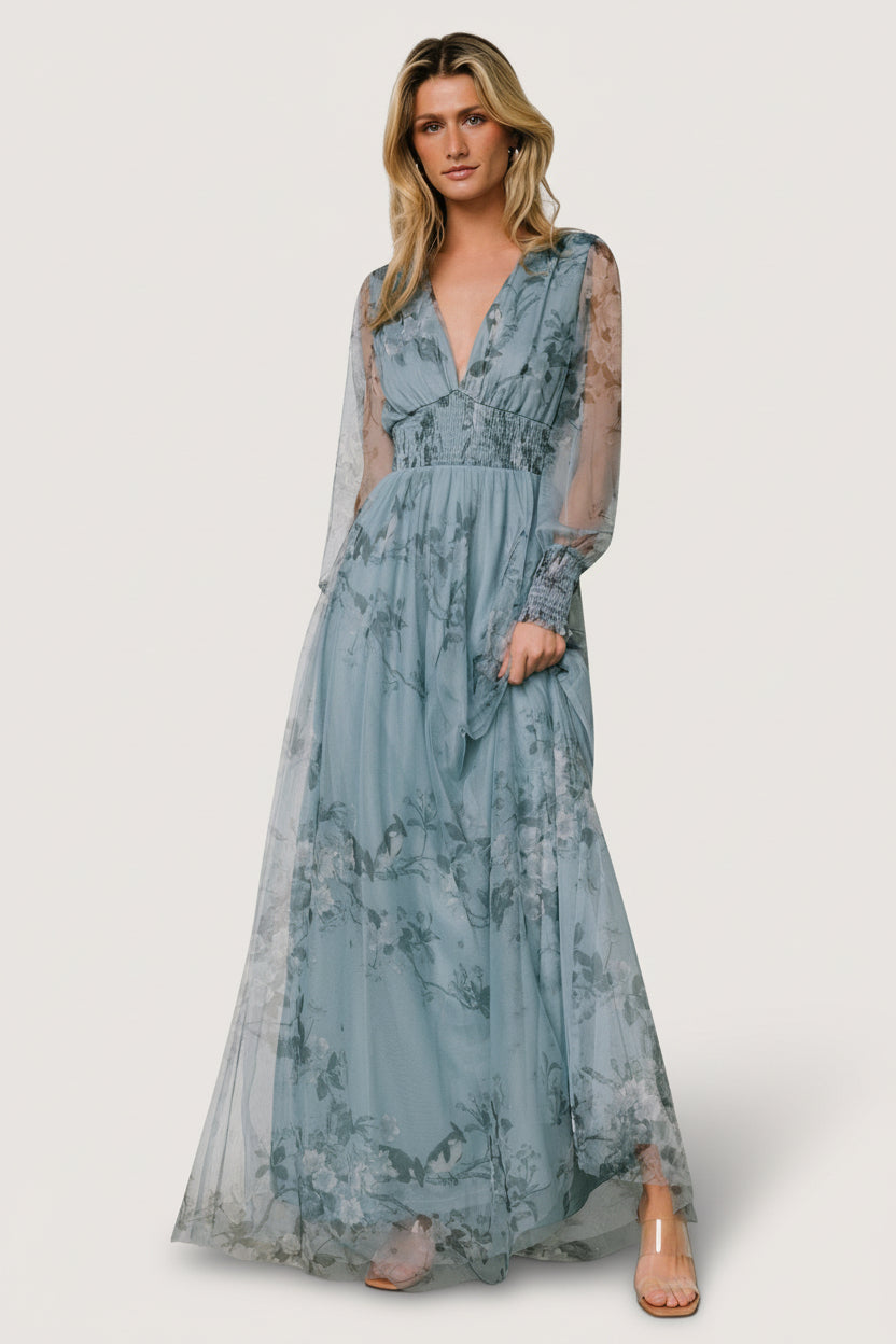 Three-quarter view showing the smocked waist detail and soft tulle overlay of the dusty blue floral maxi dress in motion.