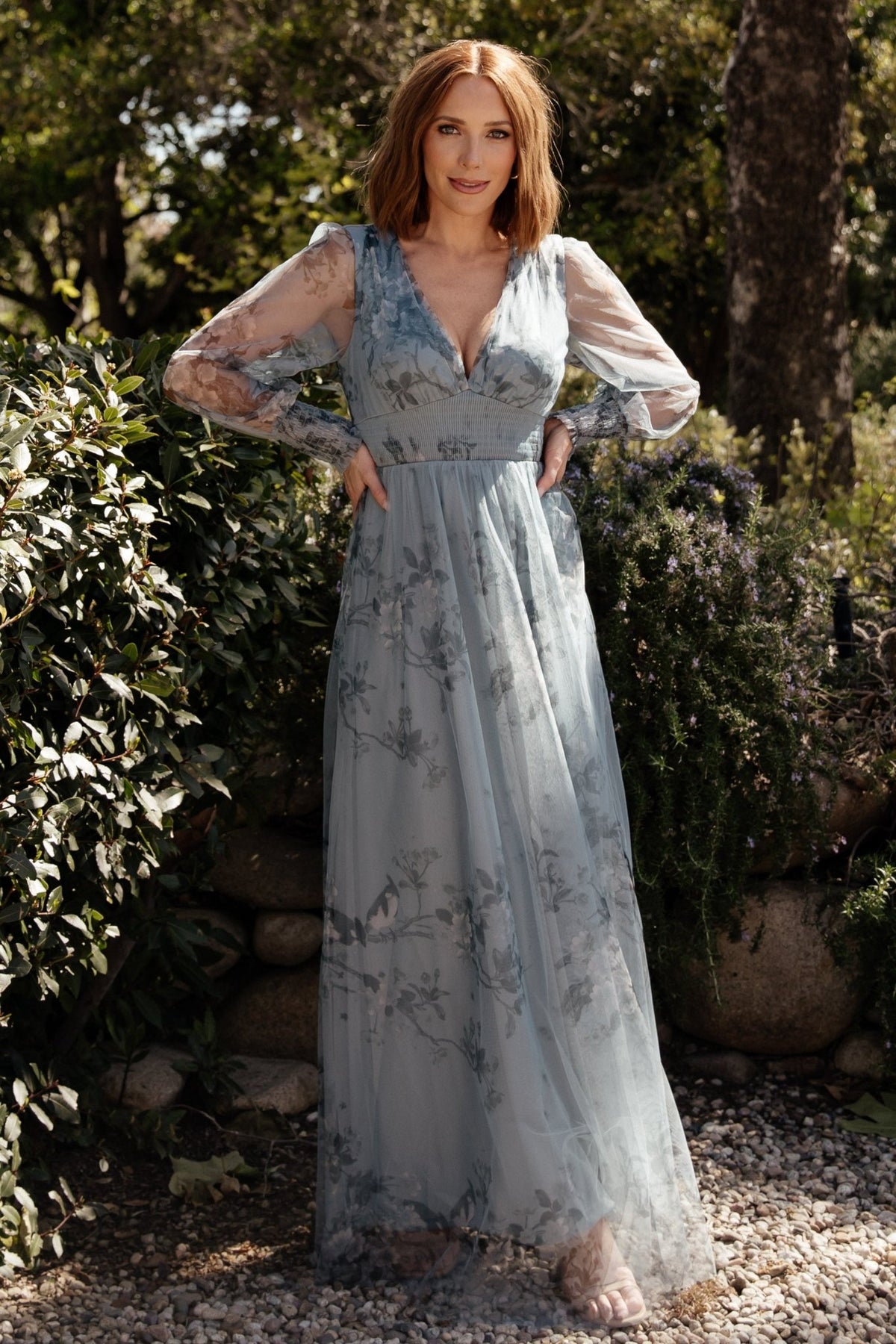 Full-length view of the dusty blue floral maxi dress styled with heels, showing length and raw hem finishing.