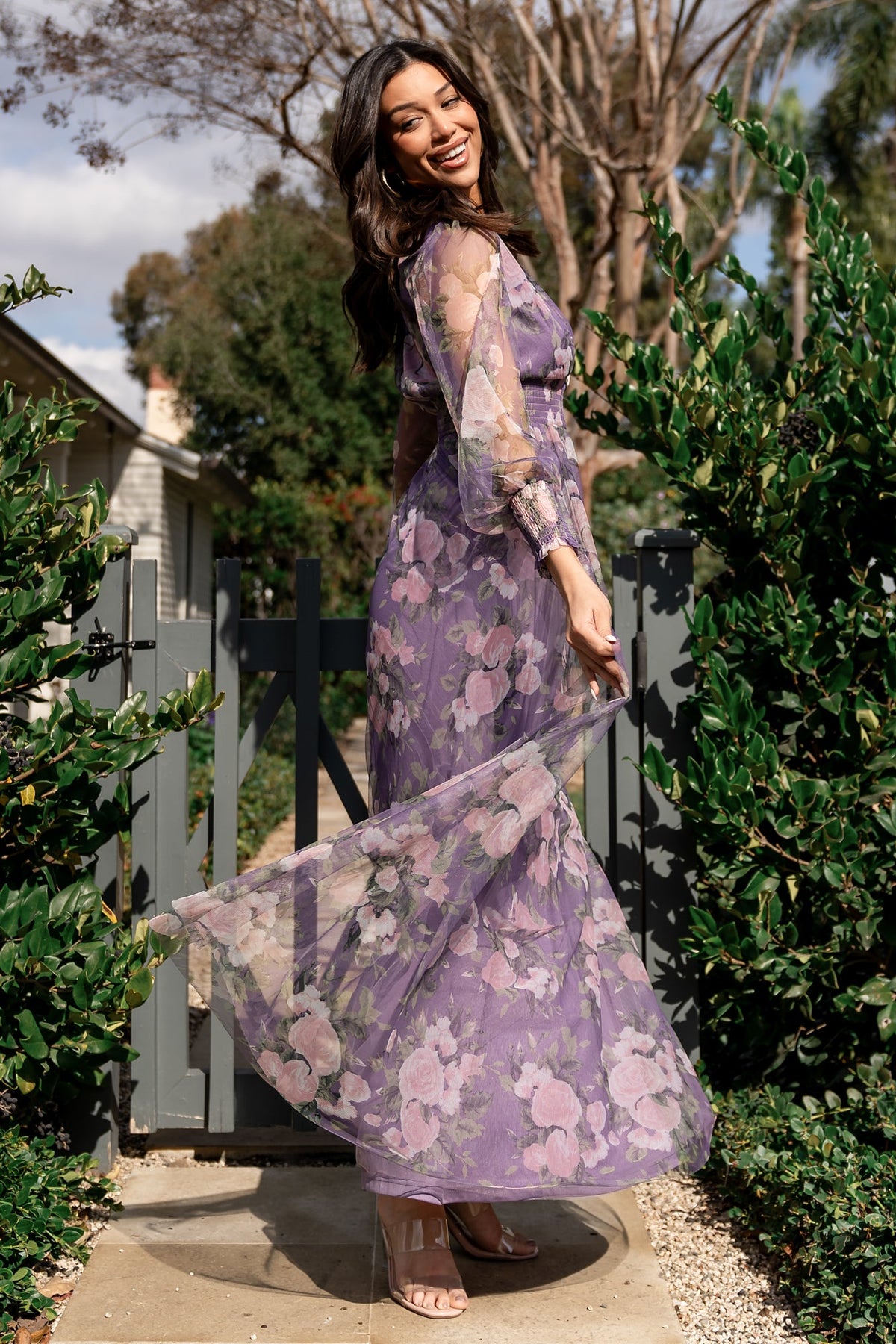 Back view of Layla Tulle Maxi Dress in lavender and blush floral print with smocked waist and long sheer sleeves for an elegant profile.