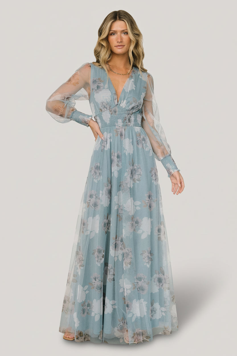 Front view of Layla tulle maxi dress in light blue floral with deep V-neck, smocked waist, long sheer sleeves, and flowing skirt, styled on model.