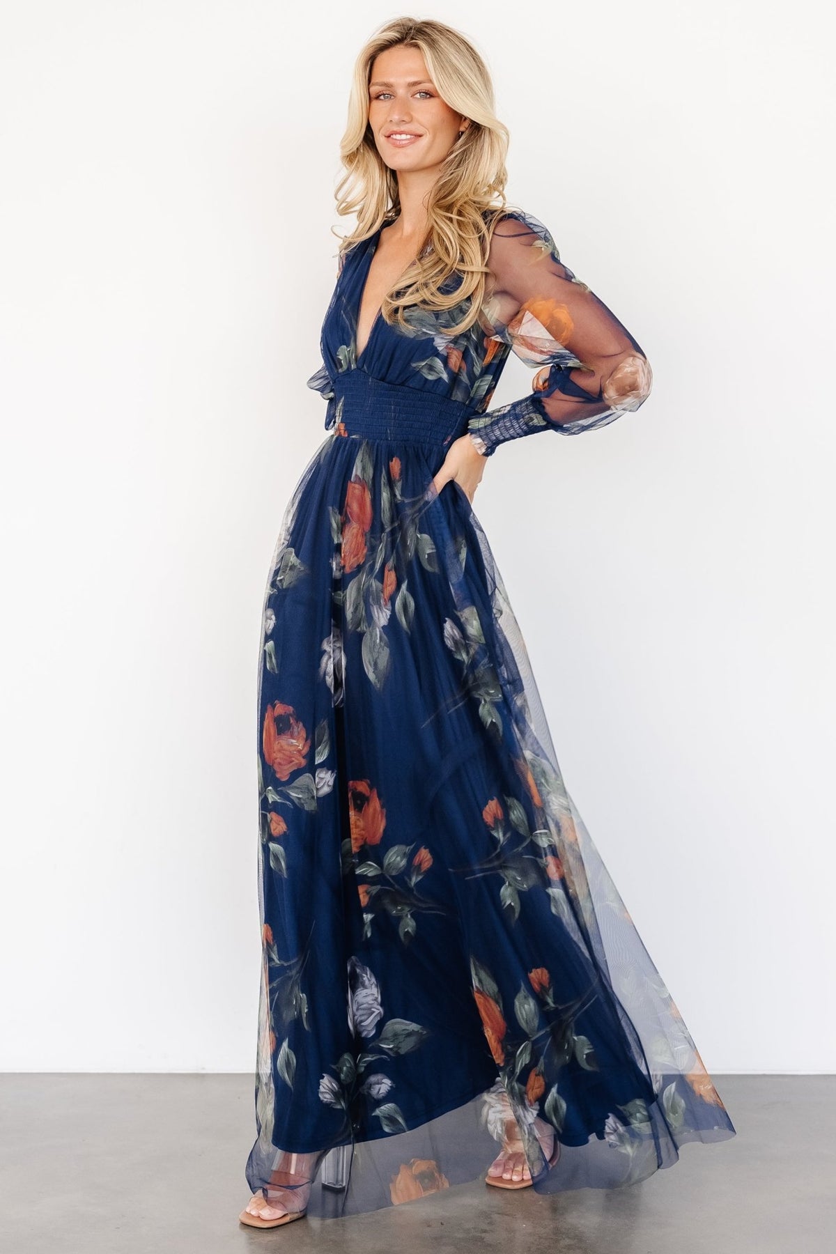 Front view of Layla Tulle Maxi Dress in navy blue floral print, showing deep V-neck, smocked waist, and long sheer sleeves.