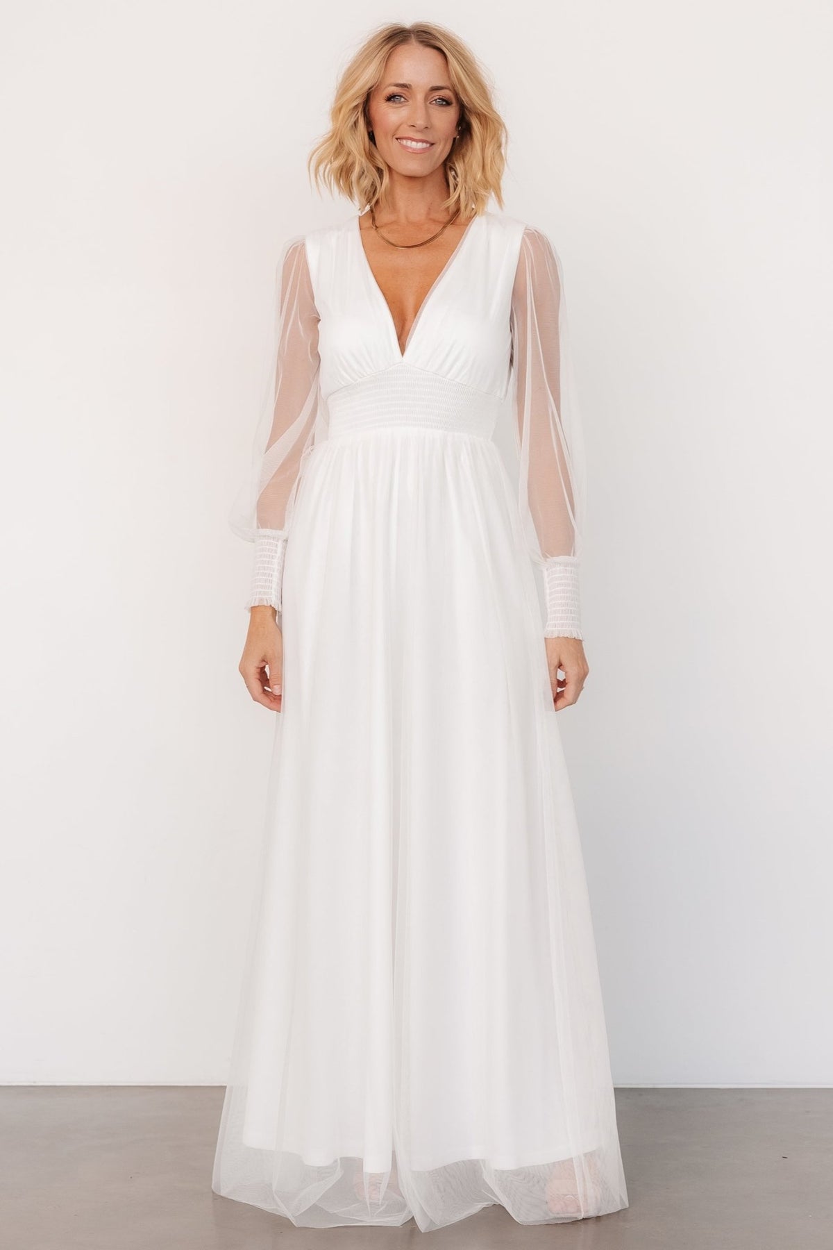 Front view of Layla Tulle Maxi Dress in white on model, showing deep V-neck, smocked cuffs and smocked waist with flowing tulle skirt.