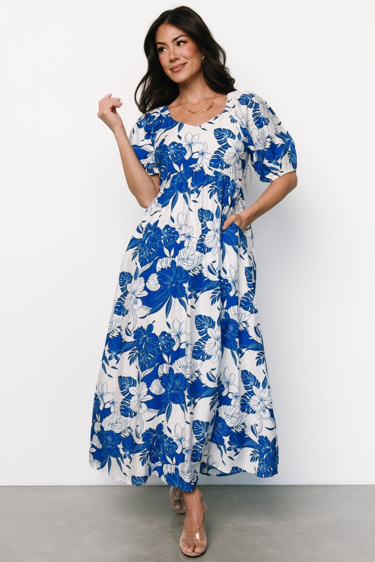 Three-quarter view of Leela maxi dress in cobalt floral print, highlighting oversized sleeves with elastic cuffs and textured rayon fabric drape.