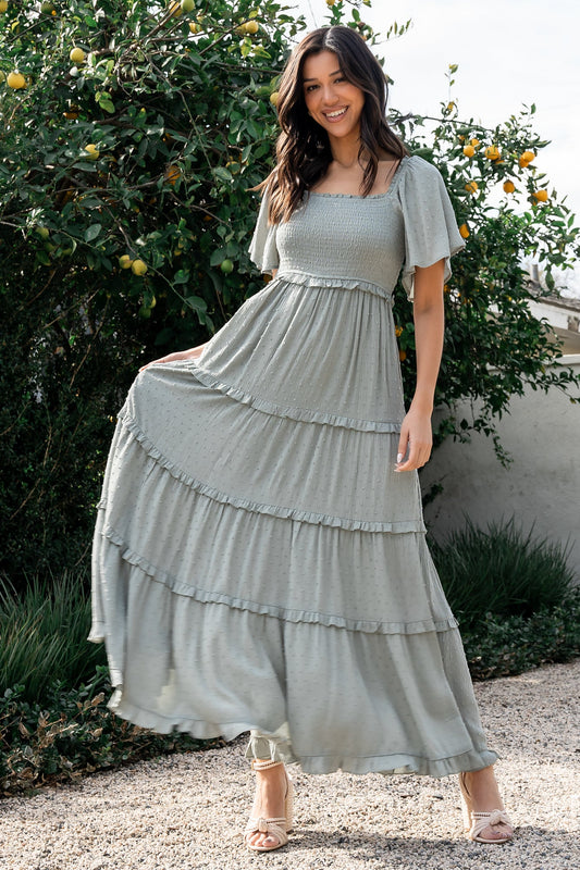 Front full-length view of Lenora smocked dotted maxi dress in sage, showing square neckline, smocked bodice, ruffle-tiered skirt, and flowing hem.