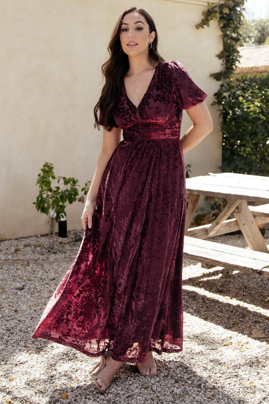 Front view of Mulberry embossed velvet maxi dress on model showing V-neck, short puff sleeves, gathered waist and side pockets.