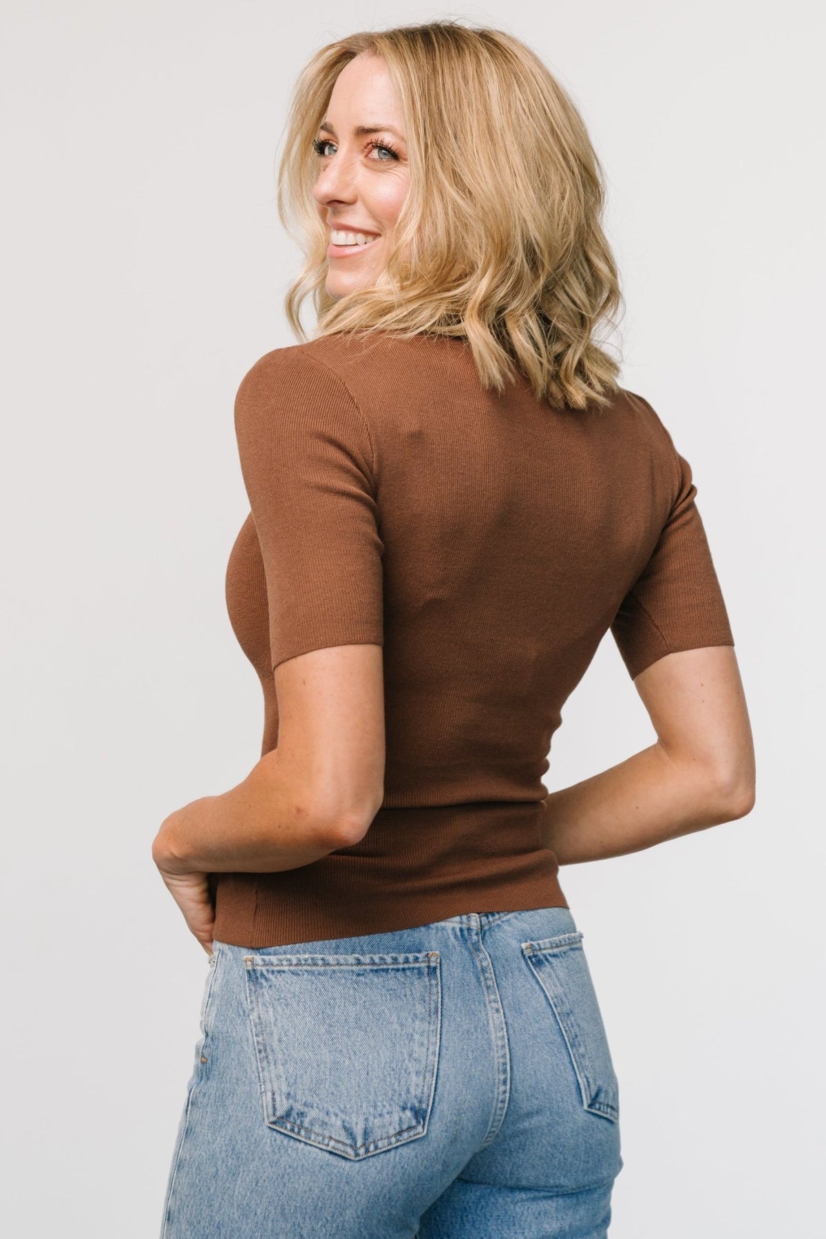 Model wearing Libby Ribbed Knit Top in warm brown — fitted view showing how the short sleeves and mock turtleneck sit on the body.