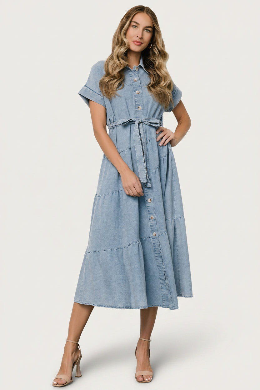 Full-length shot of model wearing washed denim midi dress styled with casual shoes to show exact length.