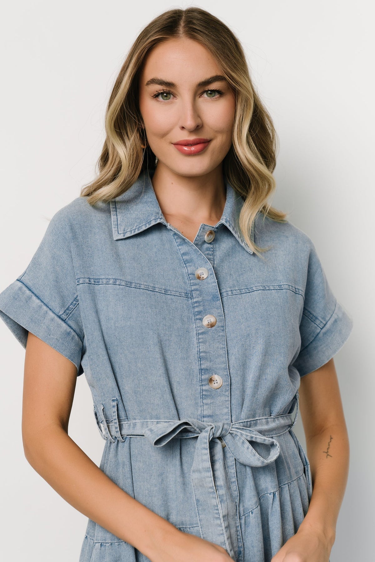 Back view of denim midi dress highlighting the tiered A-line skirt and diagonal seam details for movement.