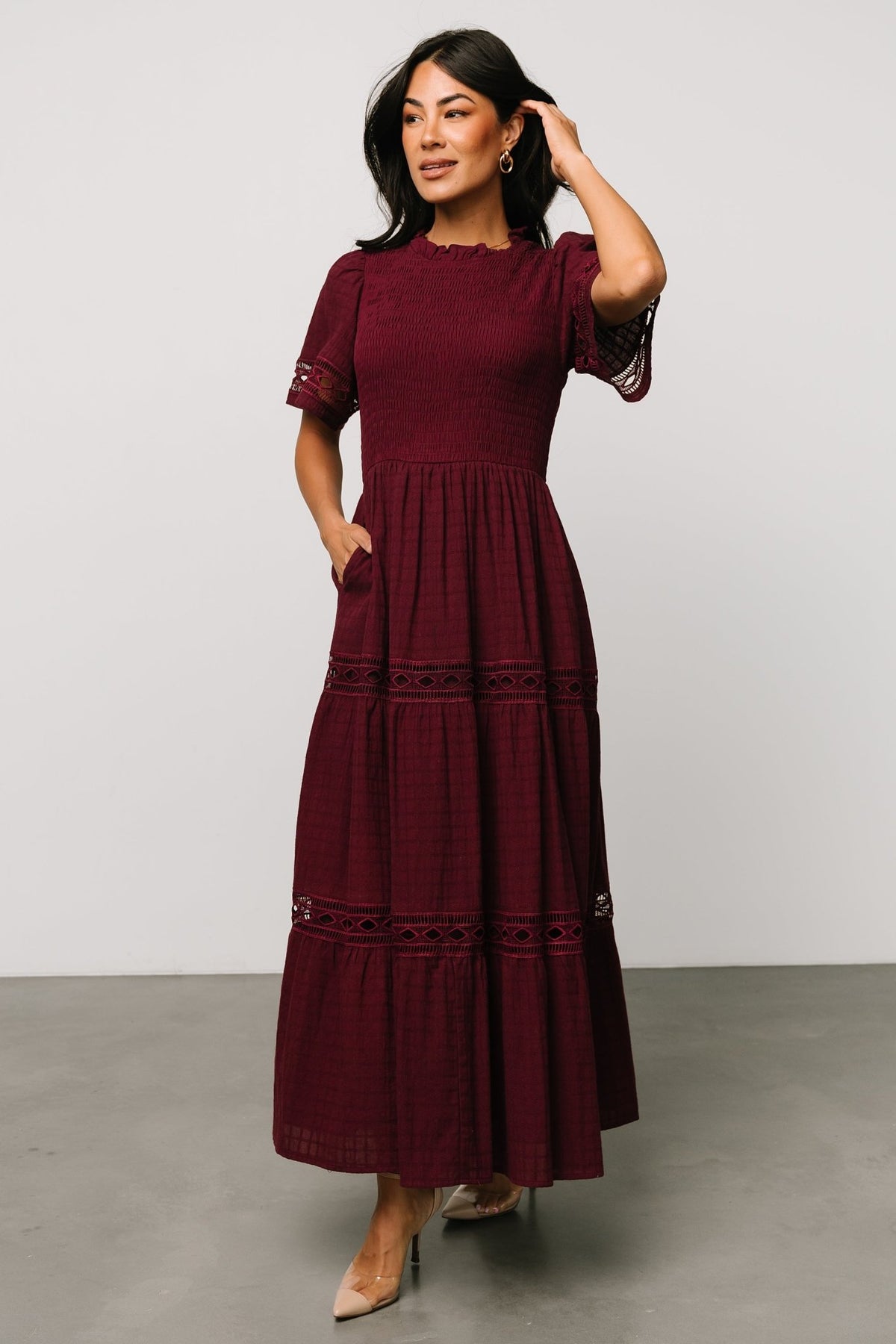 Model wearing mulberry maxi dress, angled three-quarter view highlighting oversized short sleeves and the dress’s flowing silhouette and length.