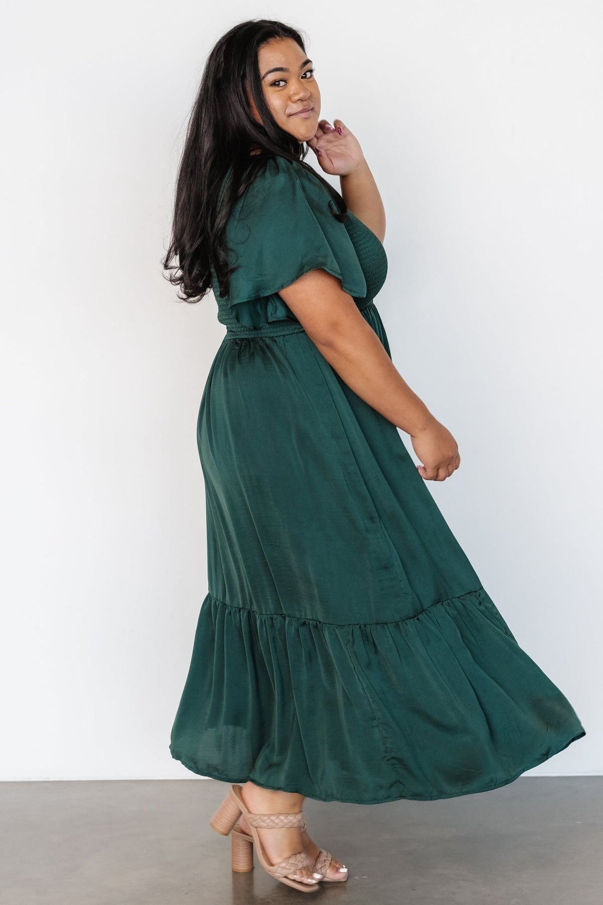 Model wearing Lovell Smocked Midi Dress in emerald styled for daytime with sandals, showing natural fabric sheen.