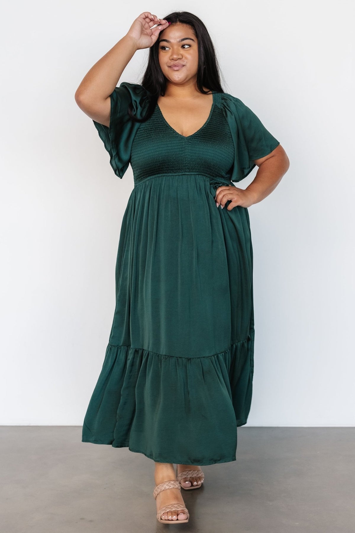 Full-length shot of Lovell Smocked Midi Dress in emerald showing midi length, semi-pleated ruffle hem, and fabric drape.