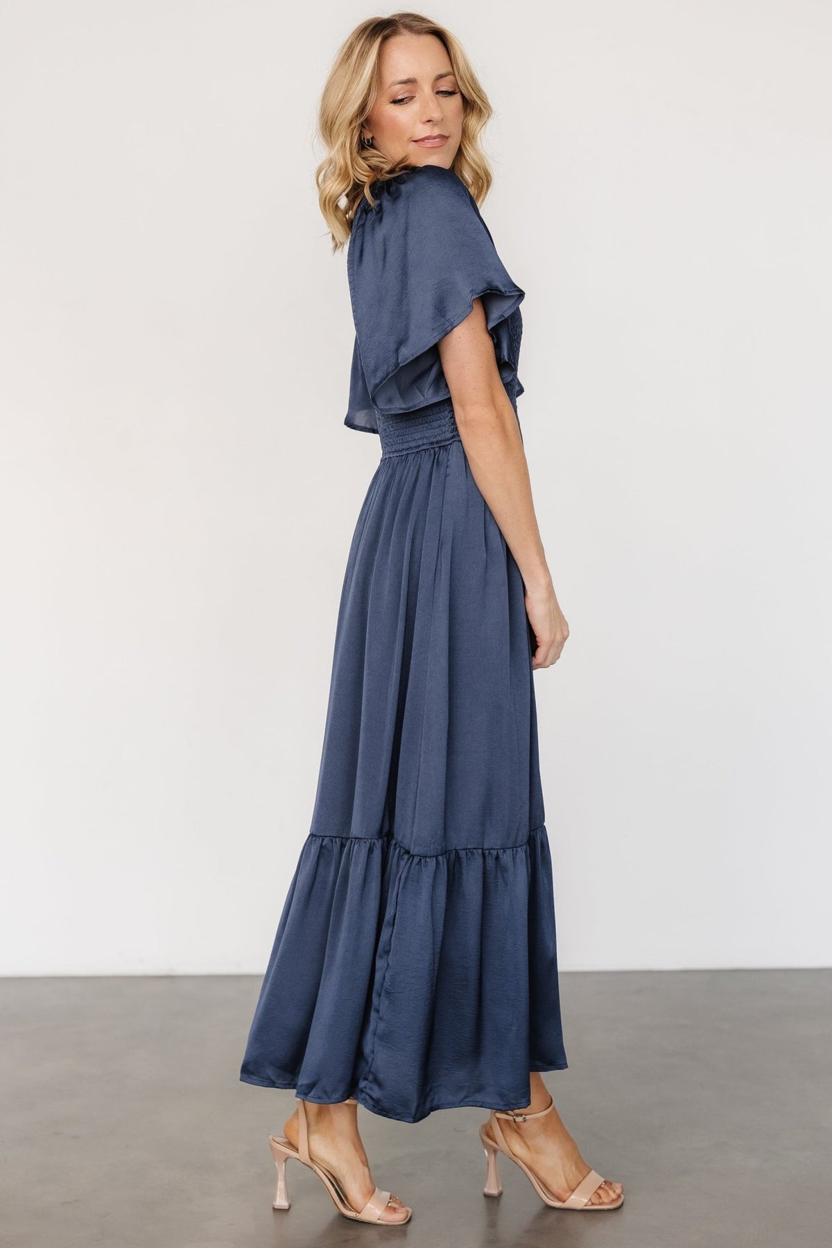 Close-up of smocked bodice and flutter sleeve showing stretch detail and rounded V neckline in deep midnight blue fabric.